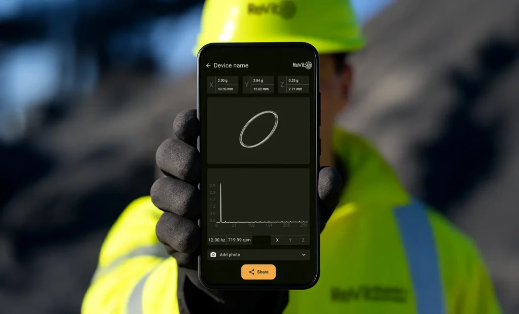ReVibe Anura Connect App on a phone in a hand of a person in warning clothes on a mining site.